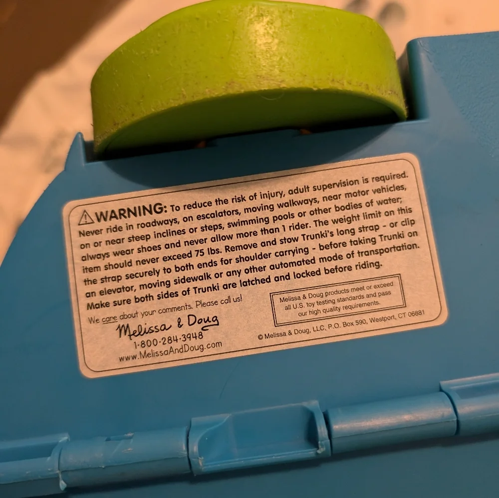 Melissa & Doug blue ride-on Trunki with green wheels and orange handle
